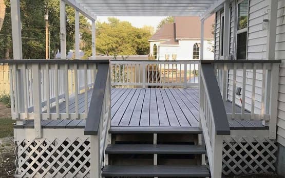 Light gray deck with white pergola and stairs leading to the backyard.