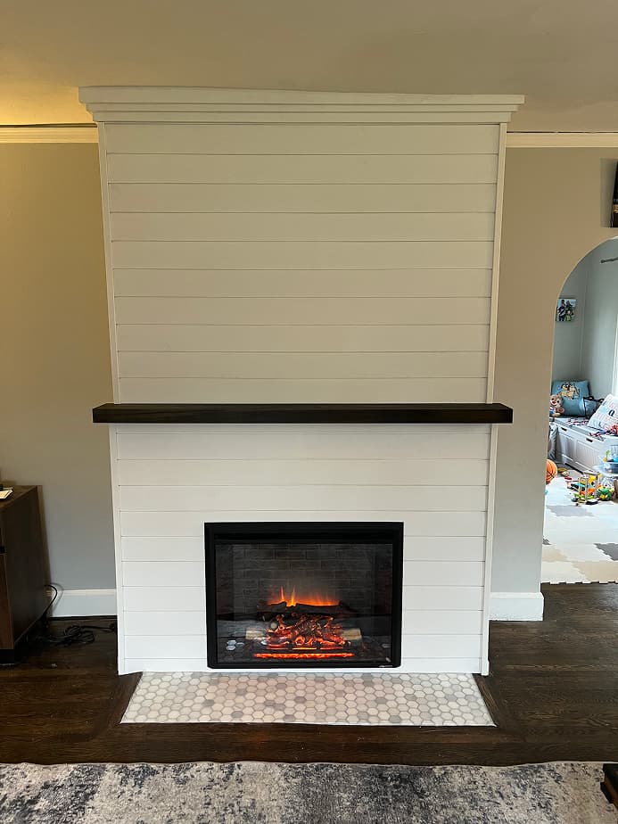 Modern fireplace remodel with white shiplap surround, dark wood mantel, and tile hearth